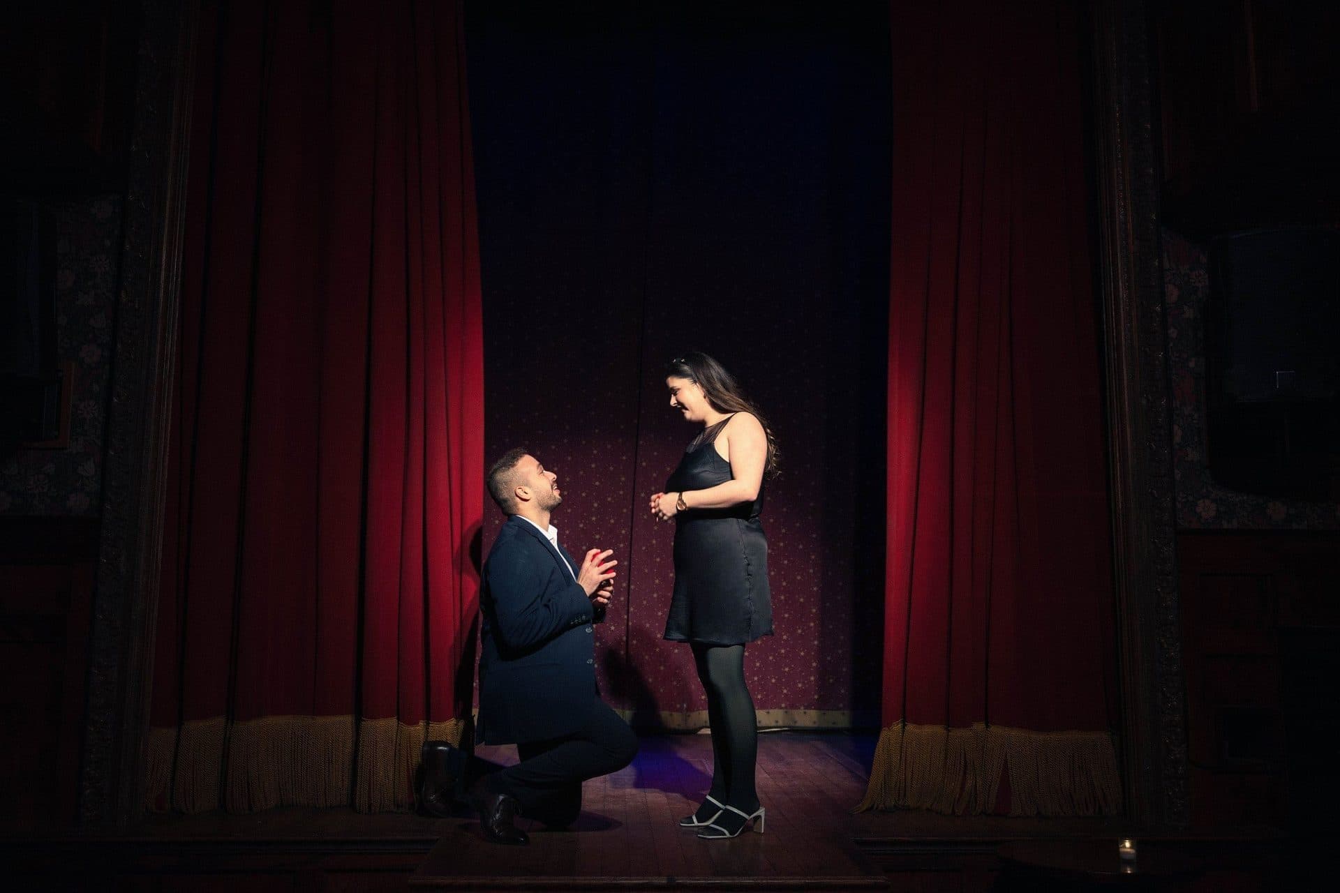 Rodolf proposing to Lexie on a red theater stage